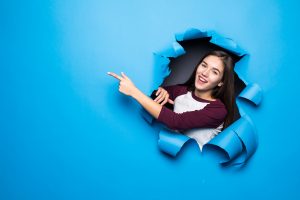 young-pretty-woman-pointed-side-while-looking-through-blue-hole-paper-wall-300x200-2